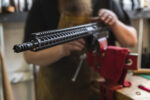 Gunsmith working on an 300 Blackout AR rifle upper receiver in a California gun shop