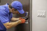 A locksmith using a screwdriver on a deadbolt lock
