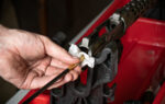 Man`s hand cleaning the gun rifle parts details by special metal cleaning rod red plastic holder background top view