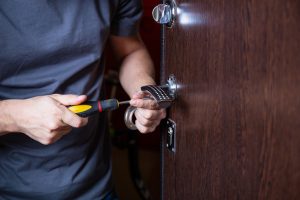 Locksmith replacing door lock to new after losing keys. Robbery protection, safety improvement. Repairman or workman changing or repair door lock.