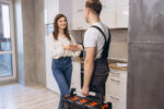 Plumber shaking hands with woman after finishing work in kitchen