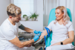 Phlebotomist taking a blood sample from a vein in the young woman arm