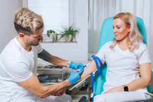 Phlebotomist taking a blood sample from a vein in the young woman arm